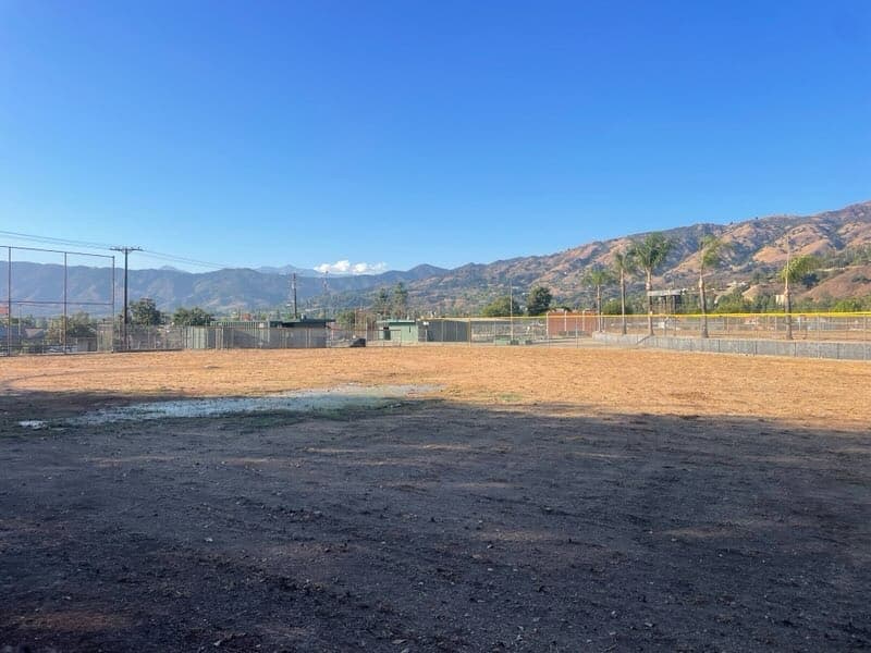 A bare-dirt field with the San Gabriel mountains in the background — unused, waiting.