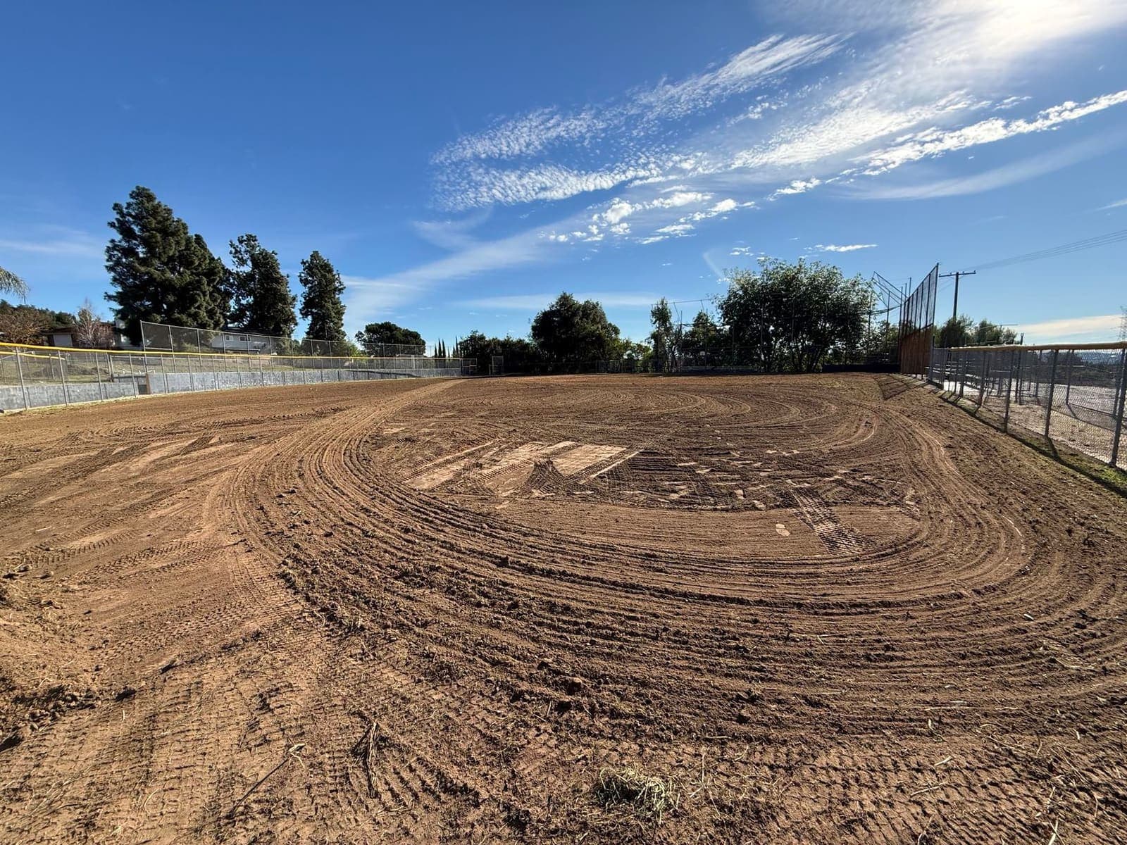 An unused infield at Sutherland — cracked dirt, idle dugouts, mountains beyond.