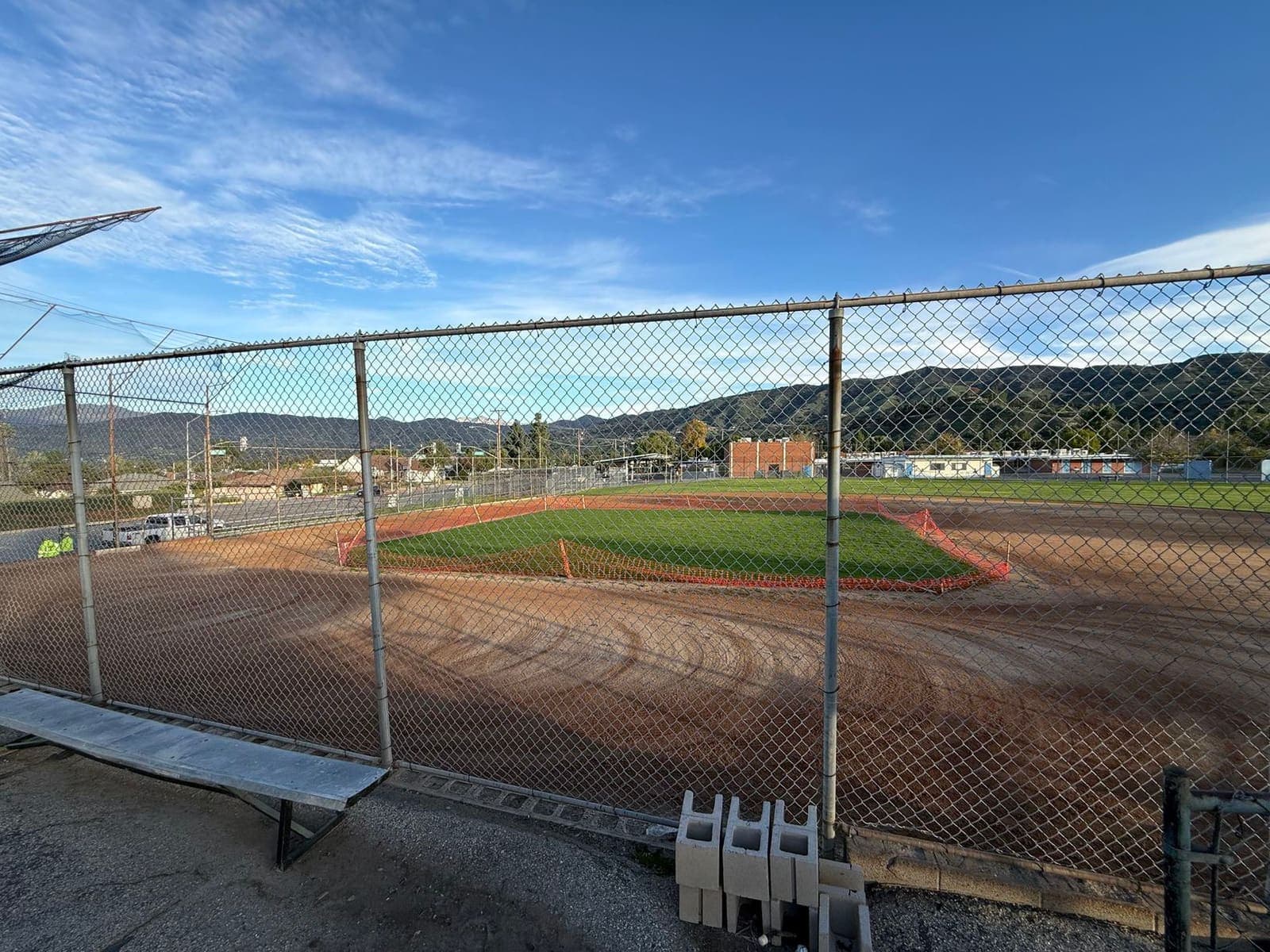 View through a chain-link fence to a half-used field — out of reach for families and kids.