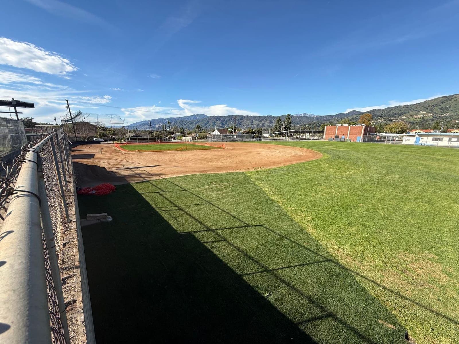 Restored Sutherland field with fresh outfield, mountains, and bright blue sky.